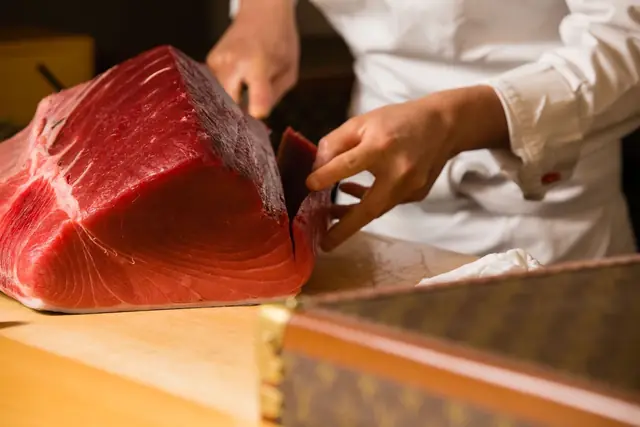 A sushi chef slicing tuna at a Tokyo counter