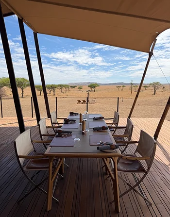 A shaded dining terrace overlooking open grassland.