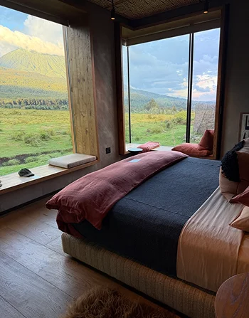 A lodge bedroom overlooking green volcanic hills.