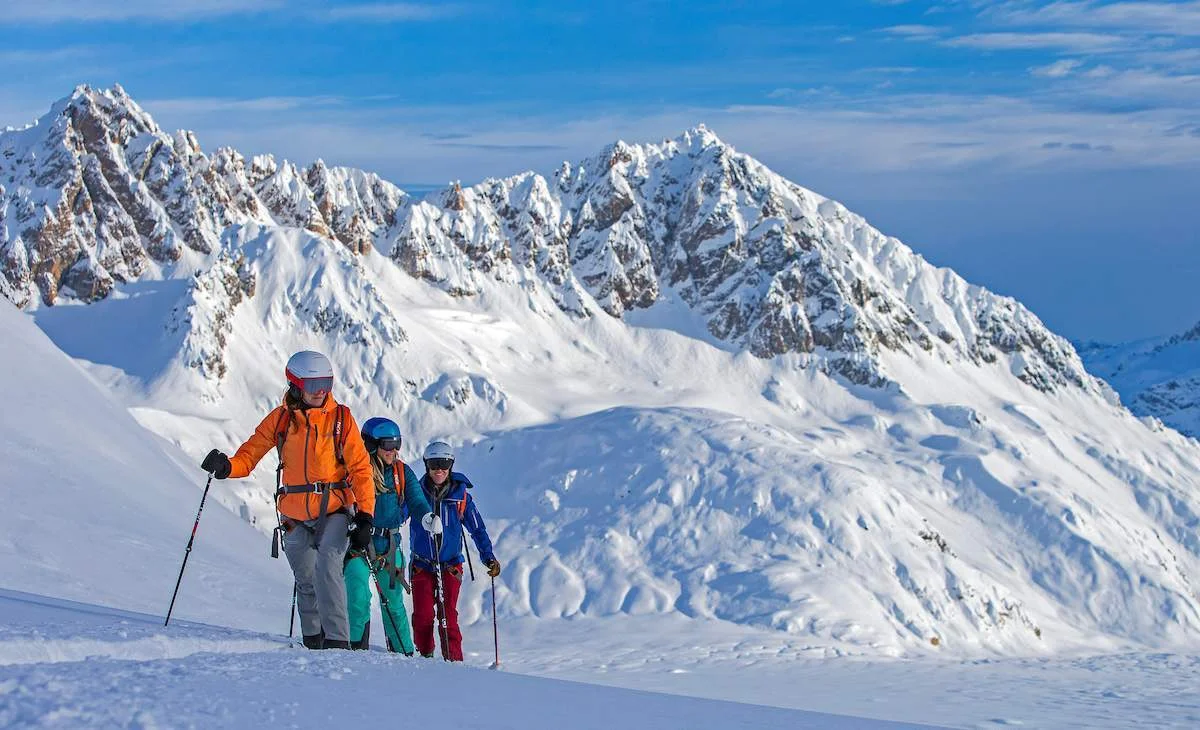 Skiers beneath the dramatic peaks of the Tordrillo Mountains in Alaska